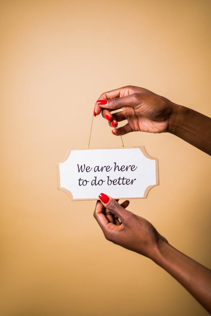 Hands holding sign with motivational message against beige background.