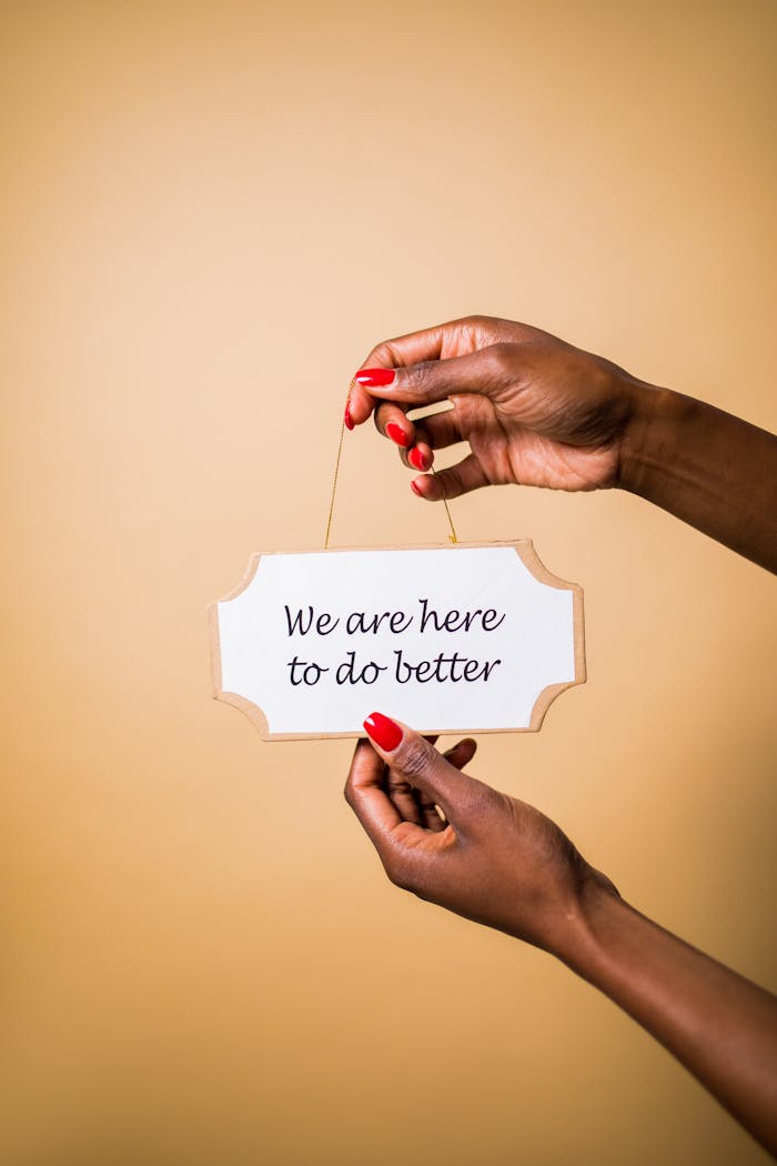 Hands holding sign with motivational message against beige background.